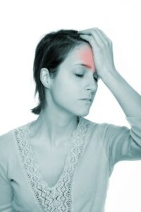 Woman holds her painful head in her hand